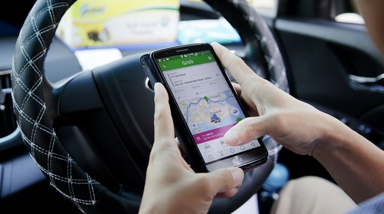 A GrabCar driver uses the Grab app on a smartphone in Singapore. Image: Ore Huiying/Bloomberg